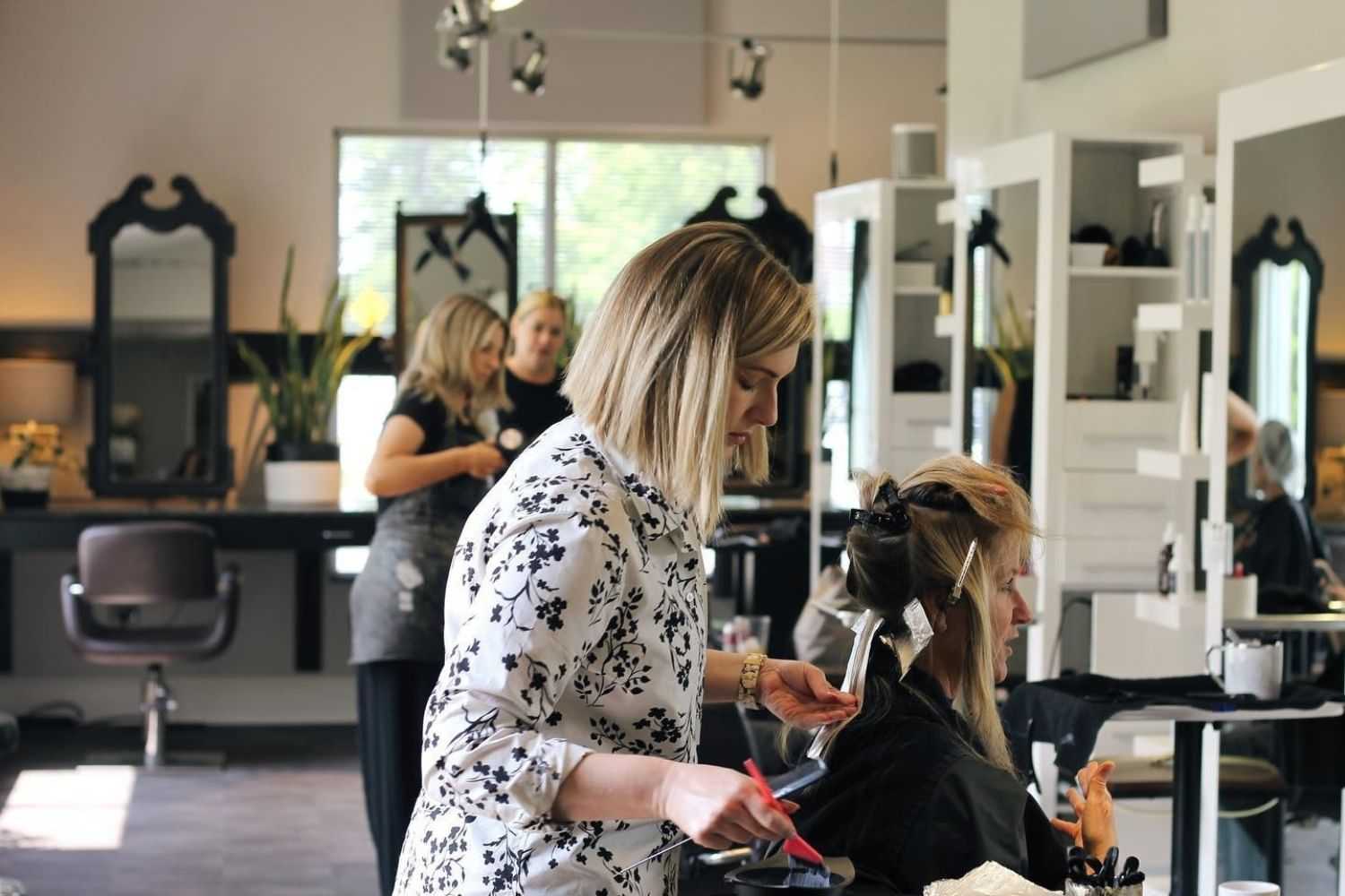 Hairdresser applying foil highlights to a client's hair in a modern salon.